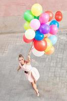 schöne Dame, die ein Bündel Luftballons hält foto