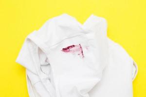 Roter Lippenstiftfleck auf weißem Hemd auf gelbem Hintergrund foto