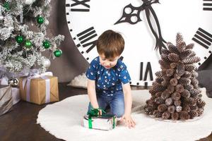 Kind sitzt mit Geschenken unter dem Weihnachtsbaum foto