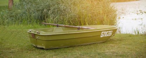 ein Boot auf dem Gras am Ufer eines ruhigen Sees foto