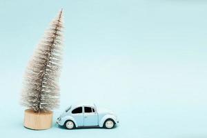 Miniatur blaues Auto mit einem Weihnachtsbaum auf blauem Hintergrund foto