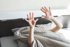 Junge schläft im Bett. Kind liegt auf Kissen und bedeckt sein Gesicht mit einer Decke foto