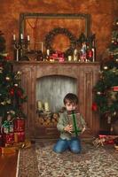 Kind Junge sitzt unter dem Weihnachtsbaum mit Geschenkbox foto