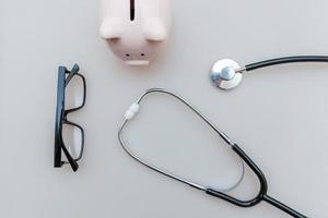 Medizin Arzt Ausrüstung Stethoskop oder Phonendoskop Sparschwein Brille isoliert auf weißem Hintergrund foto