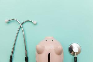 Medizin Arzt Ausrüstung Stethoskop oder Phonendoskop und Sparschwein isoliert auf trendigem pastellblauem Hintergrund foto