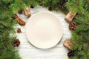 Ansicht von oben. leere platte runde keramik auf hölzernem weihnachtshintergrund. feiertagsdinnergerichtkonzept mit neujahrsdekor foto