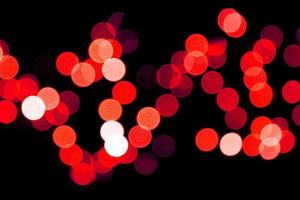 Unfokussiertes abstraktes rotes Bokeh auf schwarzem Hintergrund. defokussiert und verschwommen viele runde licht foto