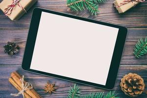 digitales tablet-modell mit rustikalen weihnachtlichen hölzernen hintergrunddekorationen für app-präsentation. draufsicht vintage, getönt mit kopierraum foto