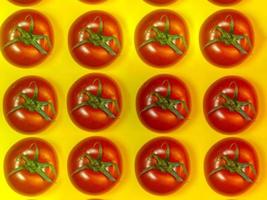 Tomate auf farbigem Papier. Gewächshaustomate auf einem Küchenbrettchen. Hintergrund aus Tomaten. foto