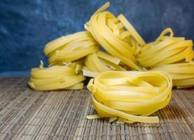 Pasta-Nester auf Weidenhintergrund. Art von Nudeln. kulinarischer Hintergrund. Kochen. foto