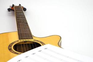 Akustikgitarre mit Musiknoten vor weißem Hintergrund. Liebes- und Musikkonzept. foto