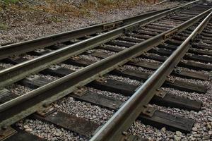 Eisenbahnkreuzungsgleise. eisenbahnreisen, tourismus.transportkonzept. Eisendetail über dunklen Steinen. schwere Industrielandschaft. technologie moderne infrastrukturentwicklung. Nahansicht foto