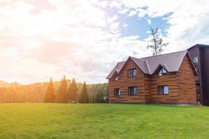 Zweistöckiges Holzhaus mit Fenstern Natur mit grünem Rasen. Verkauf oder Kauf von neuen Häusern. ein Hotel für Touristen. foto