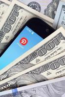 charkow, ukraine - 12. mai 2022 smartphone-bildschirm mit pinterest-app und vielen hundert-dollar-scheinen. Business- und Social-Networking-Konzept foto