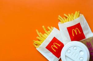 charkow, ukraine - 12. mai 2022 mcdonald's pommes frites in kleiner papiertüte und kaffeetasse auf leuchtend orangefarbenem hintergrund foto