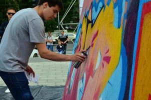 Charkow. ukraine - 2. mai 2022 festival der straßenkunst. Junge Männer malen Graffiti auf tragbare Holzwände im Zentrum der Stadt. der Vorgang des Bemalens von Wänden mit Aerosol-Sprühdosen foto