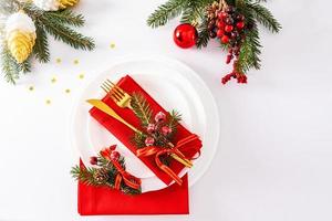 festliches servieren der weihnachtstafel in weiß-rottönen. Goldbesteck mit Schmuck verziert. Ansicht von oben. weißer Hintergrund. foto
