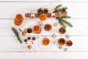 neujahrsgirlande mit eigenen händen aus öko-zutaten. getrocknete Orangen, Zapfen, Nüsse. weißer Holzhintergrund aus Brettern. foto