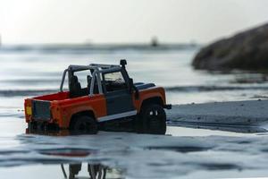 Spielzeug-Offroad-Auto zwischen Sand und Wasser in der Natur foto