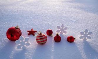 helle schmuckstücke, weihnachtskugeln, schneeflocken und sterne im schnee. Weihnachtsdekorationen foto