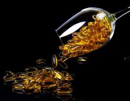 Fischölkapseln. gelbe omega-3-pillen im glas auf dem dunklen schwarz. Fischölkapseln im Weinglasglas. im Glas. in Eimerampullen foto