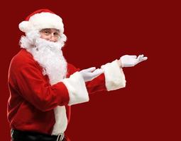 Weihnachtsmann mit ausgestreckten Armen in einer präsentierenden Geste foto