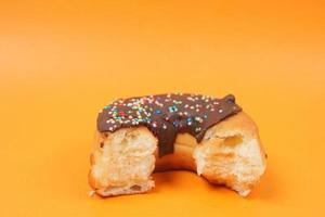 halb gegessene Donuts auf orangefarbenem Hintergrund foto