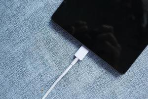 Aufladen des digitalen Tablets mit einem Kabel auf weißem Hintergrund foto
