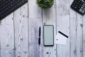 Overhead-Aufnahme von Smartphone, Kreditkarte und Stift auf dem Tisch foto