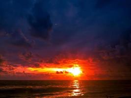 leuchtender sonnenuntergang über dem ozeanufer mit buntem himmel foto