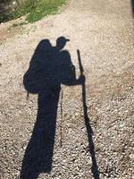 Schatten eines Wanderers mit mehreren Rucksäcken und Wanderstock foto