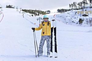 glücklich lächelnde junge frau in gelber jacke und skihelm skifahren auf einem berghang, wintersport, alpines skifahren im freien, gesunder lebensstil foto