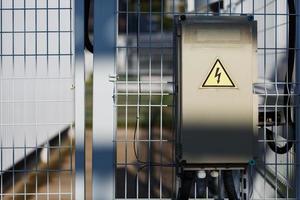 graues Klappnetzteil, elektrische Klappe. Warnschild mit gefährlicher Spannung foto