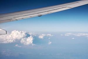 Flugzeugflügel und flauschige Wolke, Blick aus dem Flugzeugfenster foto