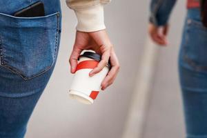 Frauenhand mit Pappbecher Kaffee zum Mitnehmen in einer Stadtstraße foto