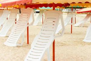 gefaltete Liegestühle und Sonnenschirme am Sandstrand foto