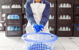 blauer plastikwasserflaschenverschluss in der hand arbeiter oder qualitätsinspektor in arbeitskleidung in der trinkwasserfabrik. trinkwassergeschäft foto