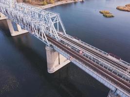 Luftaufnahme eines Gewässers mit einer Eisenbahnbrücke aus Metall auf einem Betonsockel.