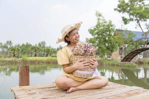 Glück, eine schöne Frau im Garten, in einen Hut gesetzt, Blumen haltend. foto