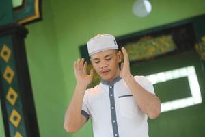 junger asiatischer muslim, der in der moschee betet foto