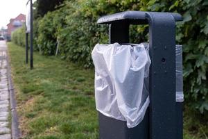 bin mit plastiktüte im grünen graspark foto