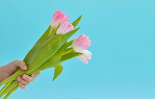 Happy Mothers Day Banner mit Kinderhand, die einen schönen Strauß Tulpen vor blauem Hintergrund mit Kopierraum für Grußtext hält. mütter oder frauentagsvorlage. foto
