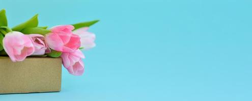 Banner mit Frühlingsblumen. rosa Tulpen auf einer Schachtel. glückwunsch.das konzept der frühlingsgeschenke und feiertage foto