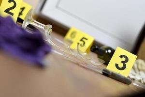 Tatortermittlung - Nummerierung der Beweismittel nach dem Mord in der Wohnung. zerbrochenes Glas Wein, Messer und Flasche als Beweismittel foto