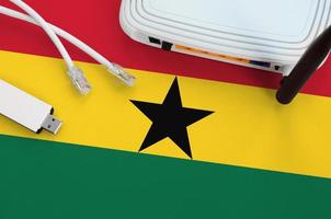 ghana-flagge auf dem tisch mit internet-rj45-kabel, drahtlosem usb-wlan-adapter und router. Konzept der Internetverbindung foto