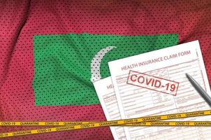 malediven-flagge und krankenversicherungsantragsformular mit covid-19-stempel. Coronavirus- oder 2019-ncov-Viruskonzept