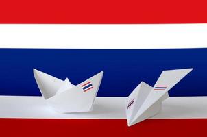 thailand flagge auf papier origami flugzeug und boot dargestellt. handgemachtes kunstkonzept foto