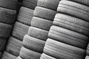 Alte gebrauchte Reifen, die mit hohen Stapeln in der Garage des sekundären Autoteilegeschäfts gestapelt sind foto