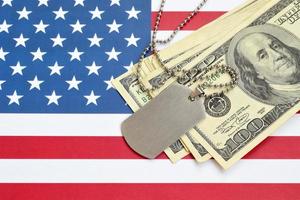 armeeidentifikationsmedaillons und dollarnoten auf der flagge der vereinigten staaten. Militärrente, Gehalt in der Armee oder Militärversicherung foto