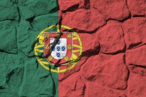 Portugal-Flagge in Lackfarben auf der alten Steinmauer in der Nähe dargestellt. strukturiertes banner auf felswandhintergrund foto